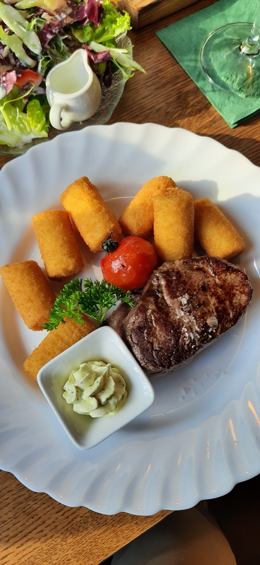 Angerichtetes Steak mit Kroketten und Kräuterbutter